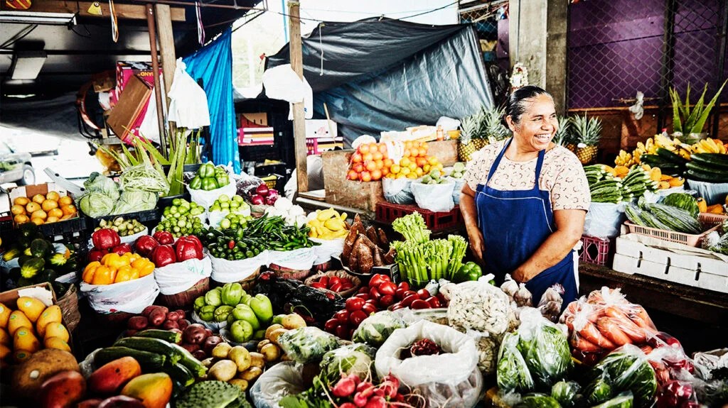 Laughing female produce vendor working at stand in marketplace