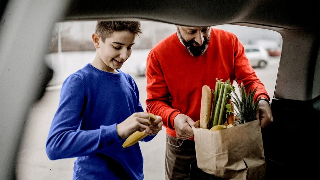 a father and son holding bags of fruit for diabetes