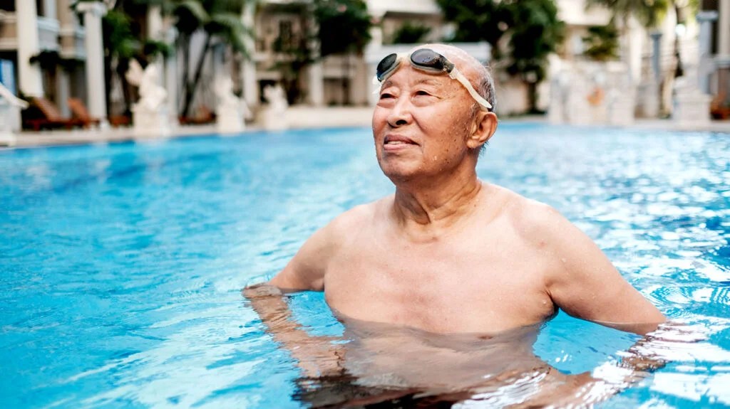 older Asian man wearing water goggles in pool