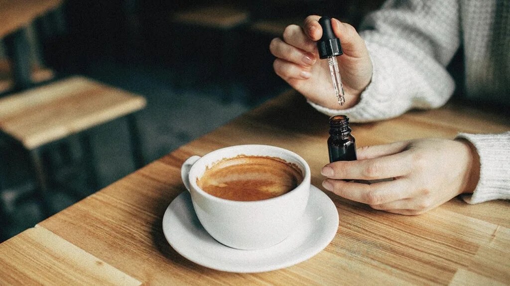 A woman adds CBD to her coffee and wonders does cbd get you high.