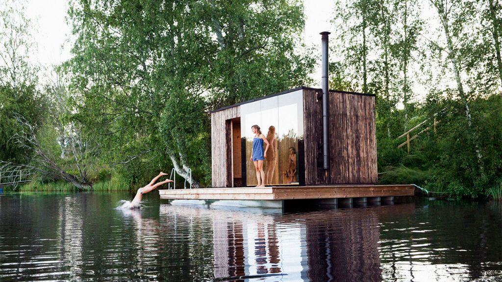 People at a sauna cabin on a lake, jumping into the water.